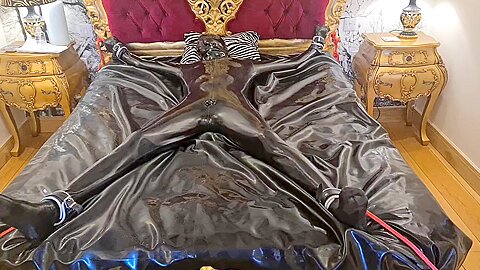 Latex-encased Woman Tied To Bed